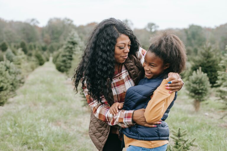 A black woman hugs a black teenage girl both smiling